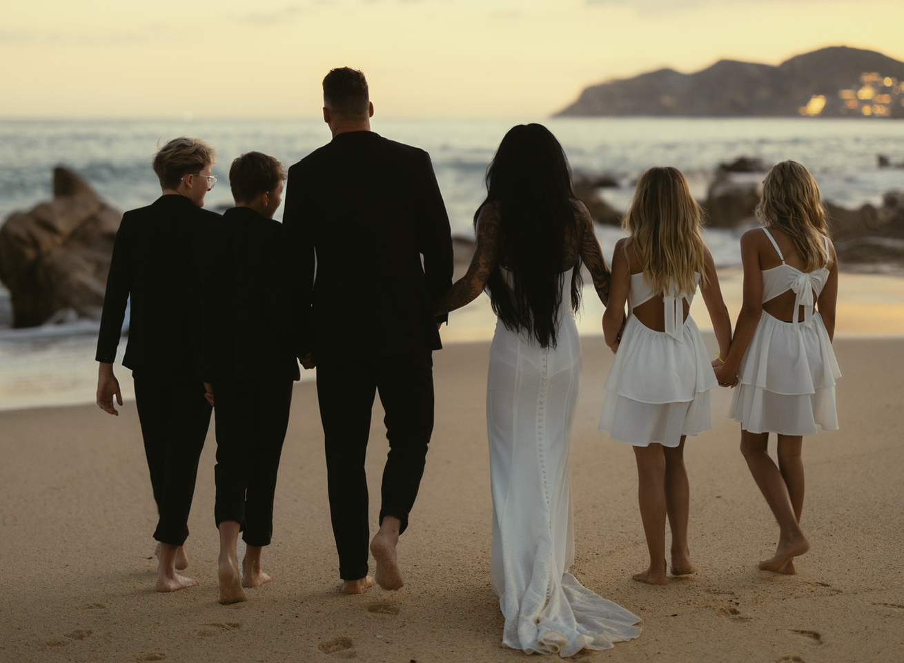 Chad and Alyssa McCloud walking on the beach at sunset with their four children